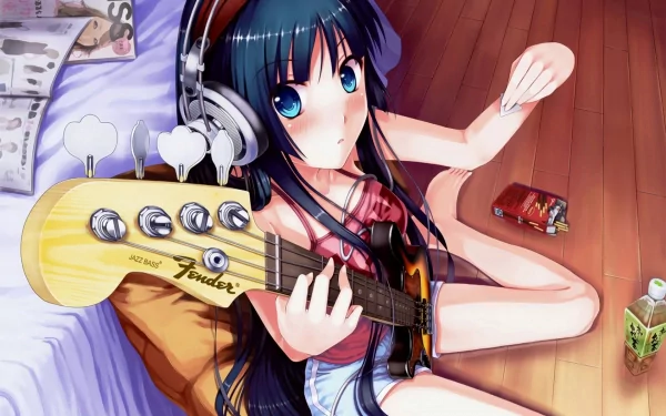 HD desktop wallpaper featuring Mio Akiyama from the anime K-ON!, playing a guitar. She is sitting on the floor with headphones, surrounded by a magazine, a drink, and a snack.