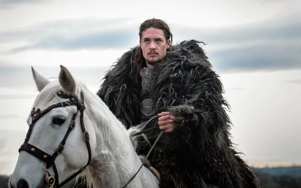 4K Ultra HD PC desktop wallpaper from the TV show The Last Kingdom: a fur-cloaked warrior rides a white horse across a misty, gray landscape.