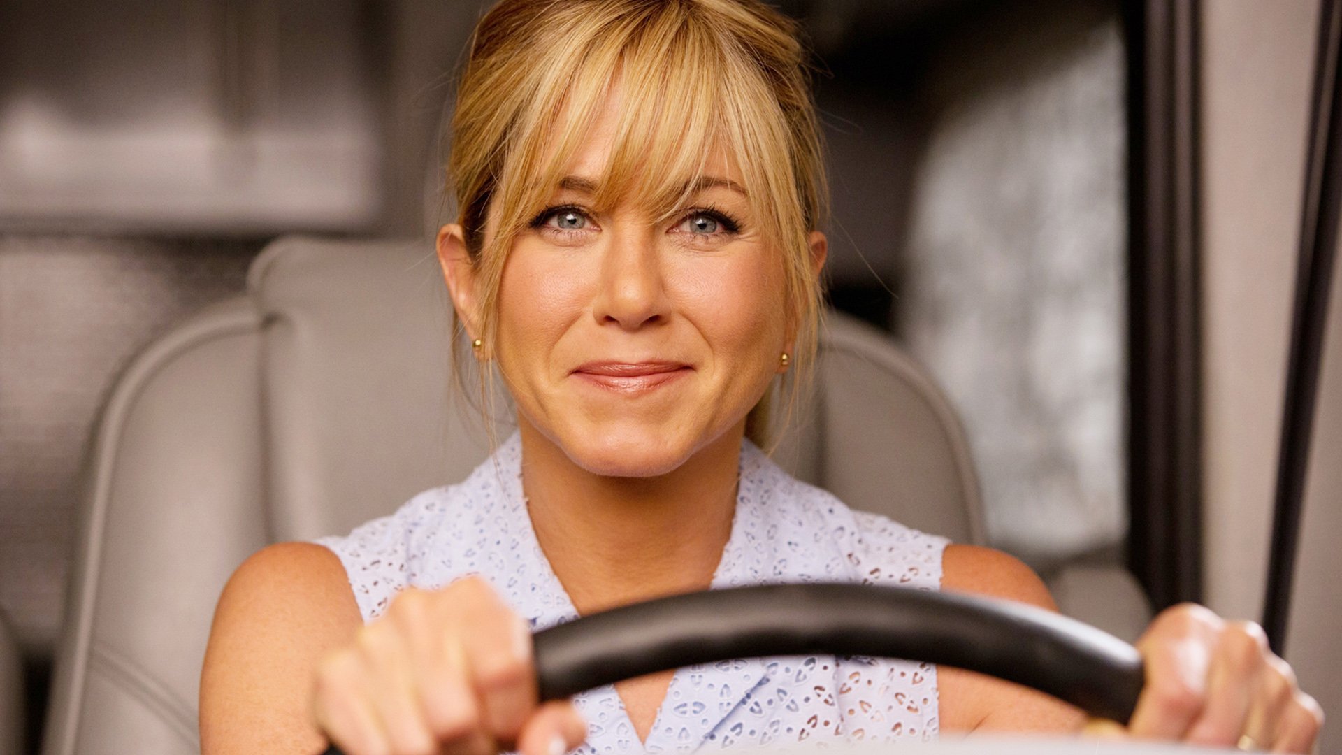 HD PC desktop wallpaper featuring Jennifer Aniston smiling while holding a steering wheel, from the movie We're the Millers.