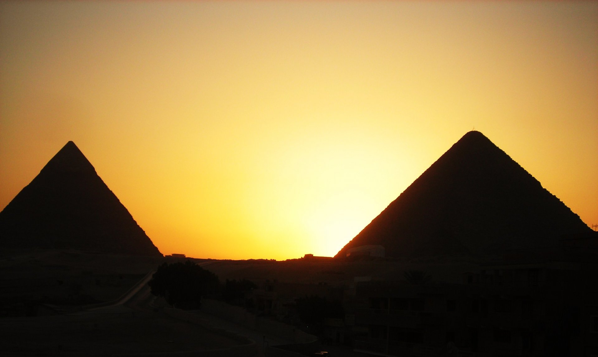 HD desktop wallpaper showing man-made pyramids silhouetted against a vibrant sunset sky.