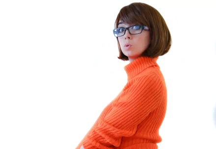 A woman cosplaying as Megan from Scooby-Doo, wearing glasses and an orange turtleneck sweater, featured in a 4K Ultra HD PC desktop wallpaper.