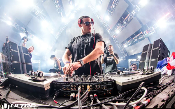 A DJ performing at a music event, creating a dynamic HD desktop wallpaper and background.