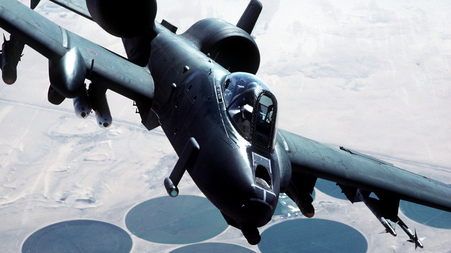 A high-definition wallpaper featuring a Fairchild Republic A-10 Thunderbolt II soaring through the sky, showcasing its military prowess against a backdrop of circular fields.