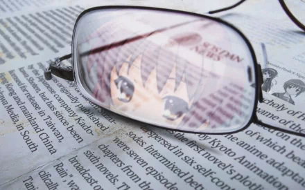 A reflective pair of glasses rests on a newspaper, featuring Yuki Nagato from *The Melancholy of Haruhi Suzumiya*, set against a visually engaging backdrop.