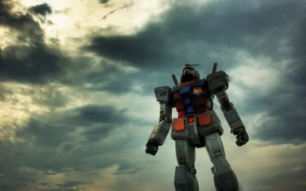 HD anime desktop wallpaper featuring a Gundam suit standing against a dramatic cloudy sky, capturing the iconic mecha from the Gundam series.