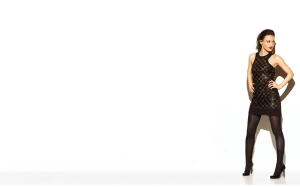 A stylish HD desktop wallpaper featuring celebrity Hilary Duff in a chic black dress, posed confidently against a minimalistic white background.