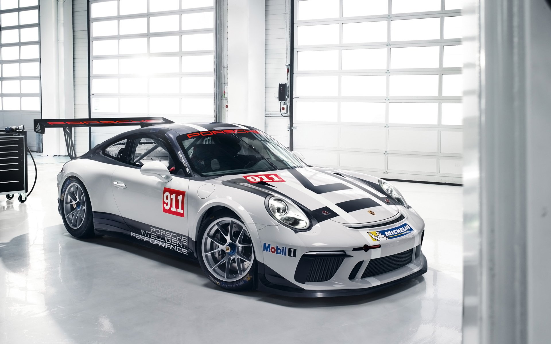 Porsche 911 GT3 Cup supercar in silver livery parked in a bright garage — high-resolution 2K Quad HD PC desktop wallpaper/background.