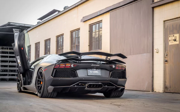 Rear three-quarter view of a matte gray Lamborghini Aventador Zaragoza Edizione supercar with scissor door open, presented as a 2K Quad HD PC desktop wallpaper and background.