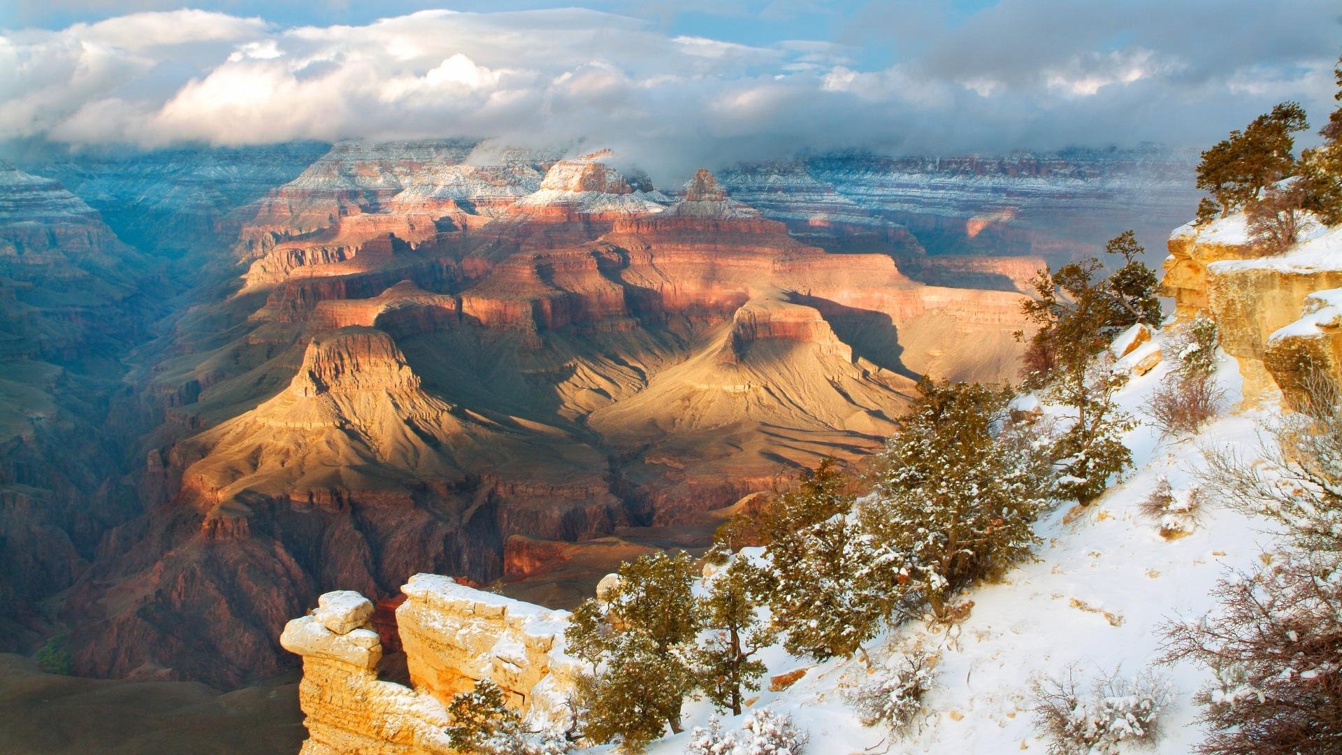 HD desktop wallpaper showcasing a snowy mountain valley and canyon under a cloudy sky, capturing the vast beauty of nature in vibrant detail.