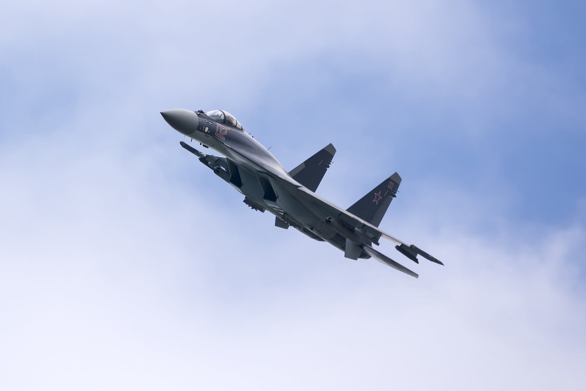 Sukhoi Su-35 jet fighter warplane in flight against a blue sky, military aircraft shown as a 2K Quad HD PC desktop wallpaper background.