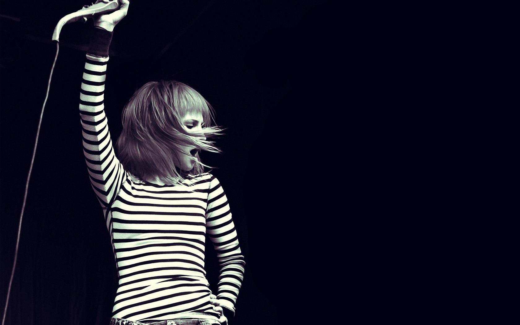 HD desktop wallpaper featuring a cute image of Hayley Williams from Paramore performing, with dynamic movement and a black and white striped outfit against a dark background.