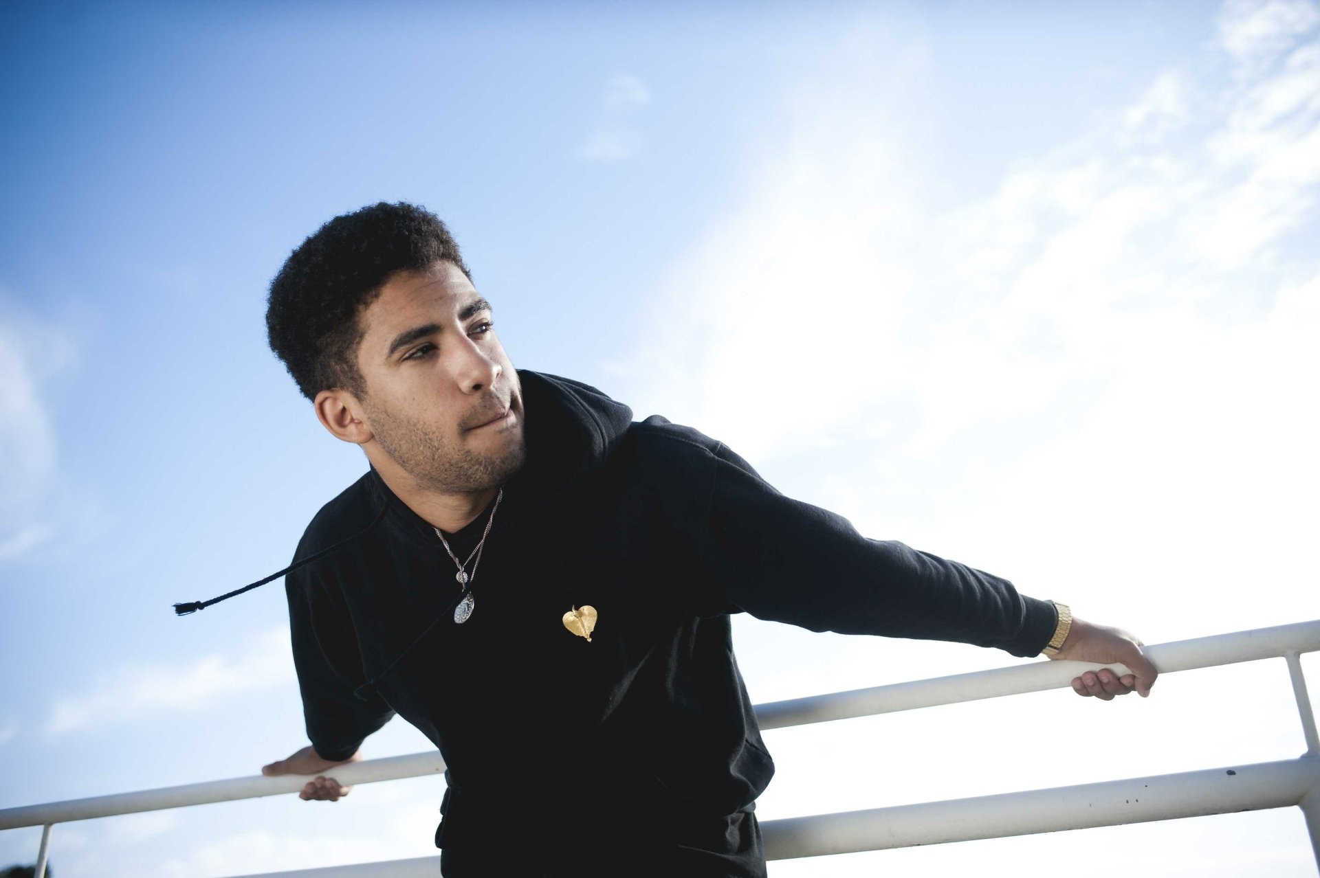 HD desktop wallpaper featuring a person named Kyle leaning on a railing with a clear blue sky background.