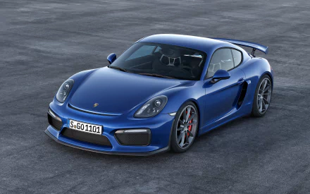 HD desktop wallpaper showcasing a sleek blue Porsche Cayman GT4 parked on a gray surface, highlighting its sporty design and iconic vehicle features.