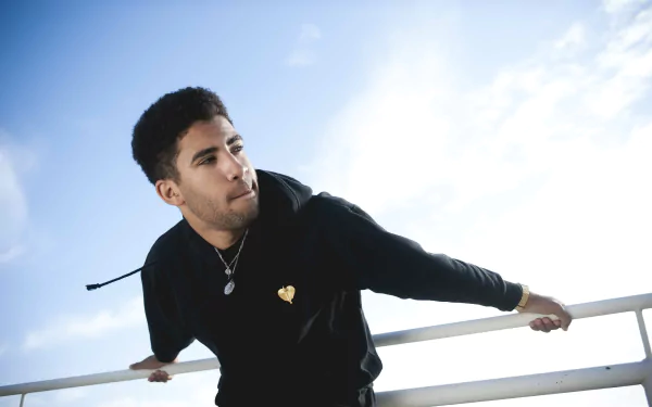 HD desktop wallpaper featuring a person named Kyle leaning on a railing with a clear blue sky background.