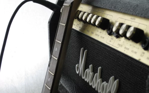 A close-up of a guitar neck connected to a Marshall amplifier, capturing the essence of music in a striking HD wallpaper for desktop backgrounds.