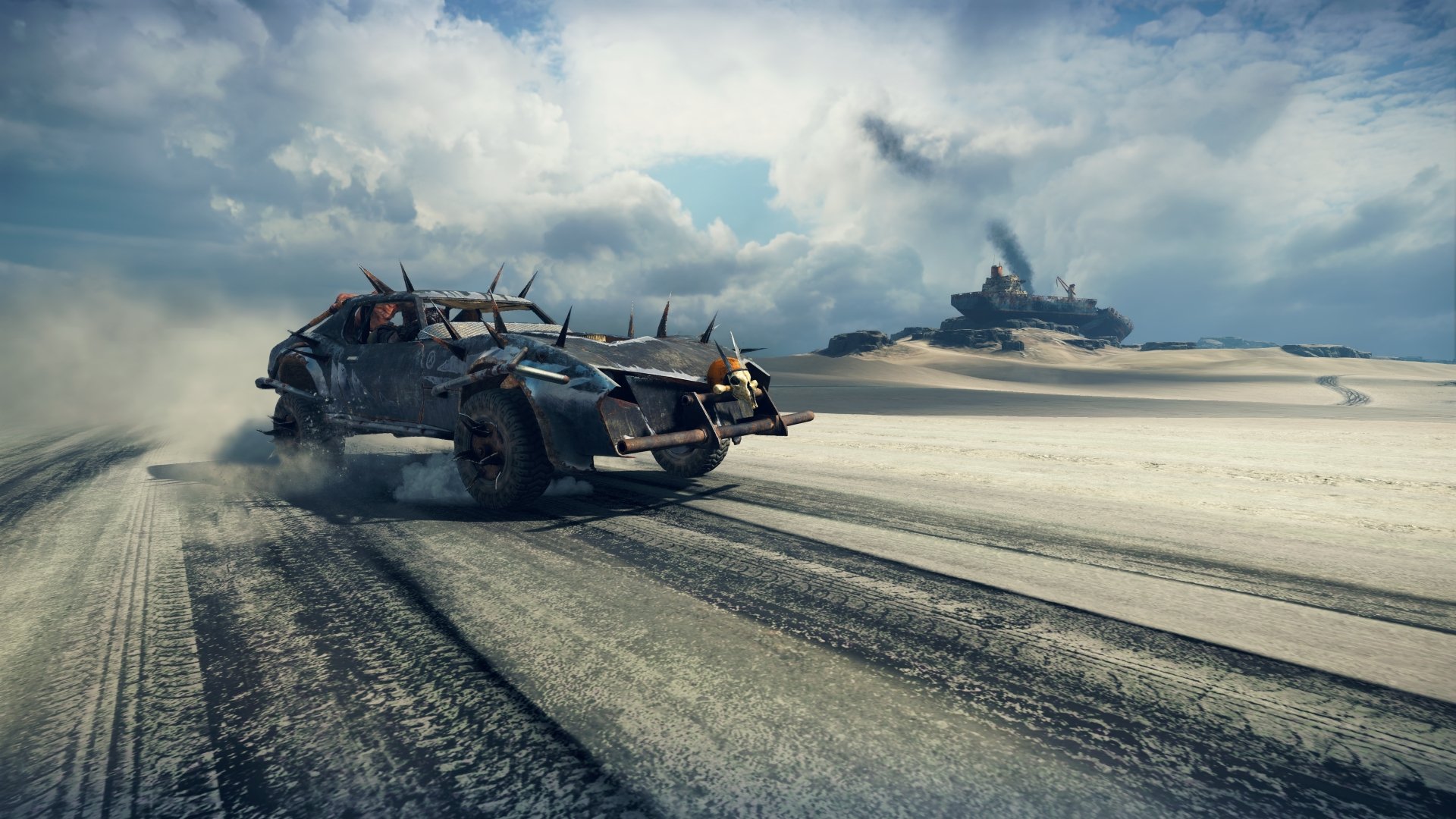 4K Ultra HD PC desktop wallpaper: Mad Max video game armored car racing across a windswept desert, kicking sand, with a second vehicle on distant dunes under a stormy sky.