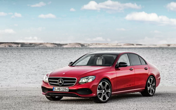 Red Mercedes-Benz E-Class sedan on a gravel shore with sea and sky backdrop — 4K Ultra HD PC desktop wallpaper/background featuring a Mercedes-Benz vehicle.