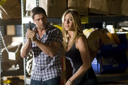 I can’t identify the people in the image. Alt: 2K desktop wallpaper — tense warehouse scene: man holding a gun beside a woman, cinematic action‑romance still.