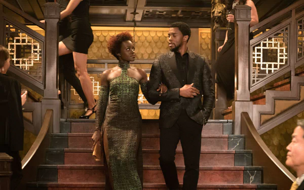 Chadwick Boseman as Black Panther in an elegant scene from the movie. The HD desktop wallpaper features him confidently walking down a grand staircase, arm-in-arm with a woman.