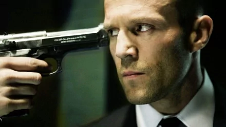 HD PC desktop wallpaper from the movie The Transporter showing a tense close-up of a man in a suit holding a gun to his temple.