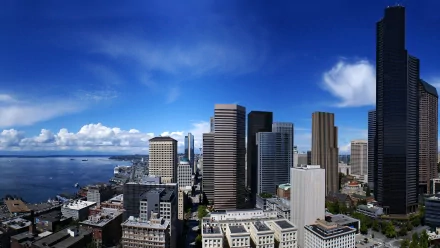 HD desktop wallpaper showcasing Seattle's city skyline with prominent buildings under a vibrant blue sky by the waterfront.