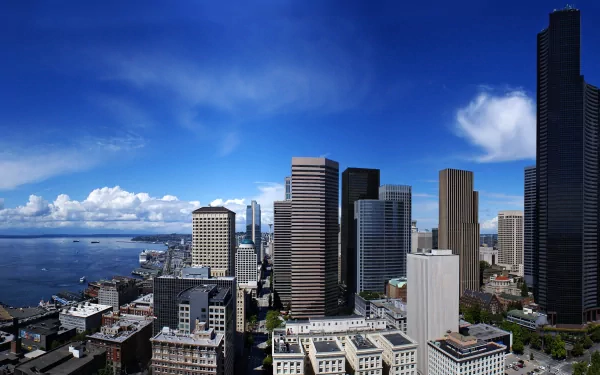 HD desktop wallpaper showcasing Seattle's city skyline with prominent buildings under a vibrant blue sky by the waterfront.