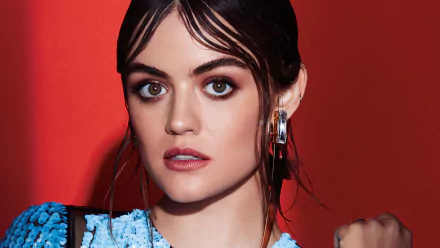 HD PC desktop wallpaper featuring celebrity Lucy Hale against a bold red background, showcasing her striking makeup and sleek hairstyle.