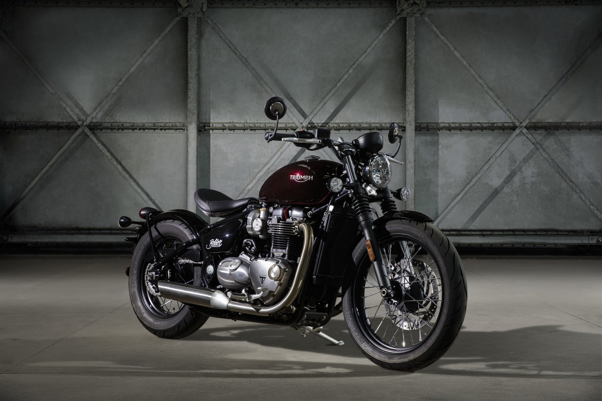 A sleek Triumph Bonneville motorcycle showcased against a textured industrial backdrop, captured in stunning 4K Ultra HD for PC desktop use.