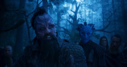 HD PC desktop wallpaper from Guardians of the Galaxy Vol. 2 — bearded, tattooed alien leader in a misty blue forest, blue-skinned companion and shadowed figures behind.