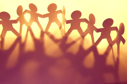 HD wallpaper featuring silhouette of paper chain of friends holding hands with a motivational vibe on a warm, glowing background.