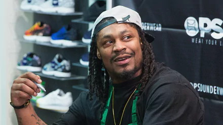 HD desktop wallpaper featuring Marshawn Lynch with a backdrop of shoes, representing the Seattle Seahawks.