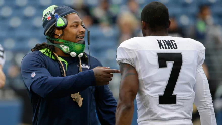Marshawn Lynch interacts with a teammate before a game, showcasing the camaraderie of the Seattle Seahawks. A vibrant HD wallpaper capturing sportsmanship and teamwork.