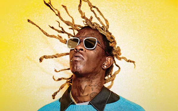 HD desktop wallpaper featuring a person with sunglasses and dynamic dreadlocks against a vibrant yellow background.