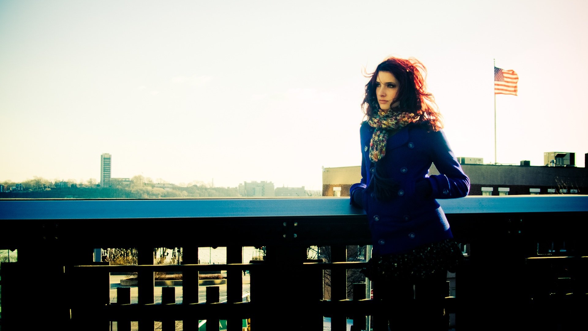 HD photography of celebrity Susan Coffey standing outdoors by a railing with an American flag in the background, designed as a PC desktop wallpaper and background.
