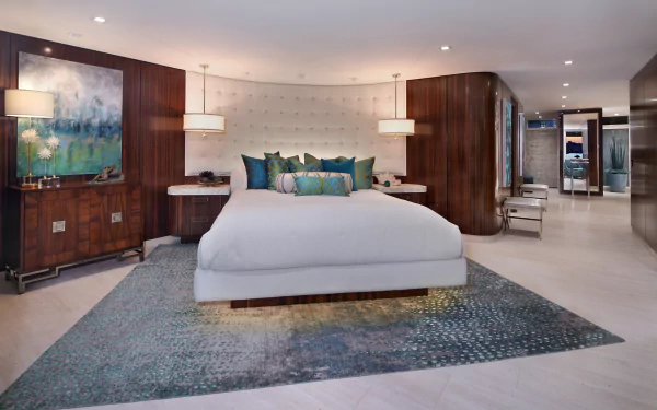 A modern bedroom features a large bed with plush pillows, rich wood paneling, soft lighting, and contemporary furniture, captured in a 4K Ultra HD desktop wallpaper.