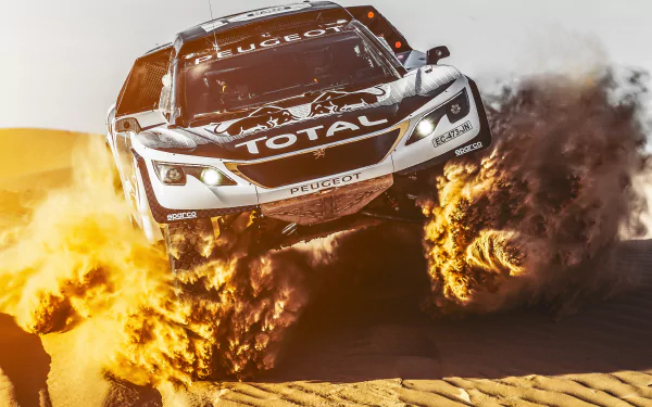 A rally car kicking up sand while airborne on a desert track, captured in dynamic motion as an HD PC desktop wallpaper and sports background.