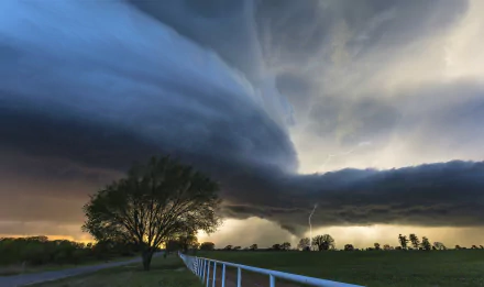 A dramatic 4K Ultra HD desktop wallpaper featuring lightning striking near a tornado over a field, with a fence and a lone tree under stormy skies.