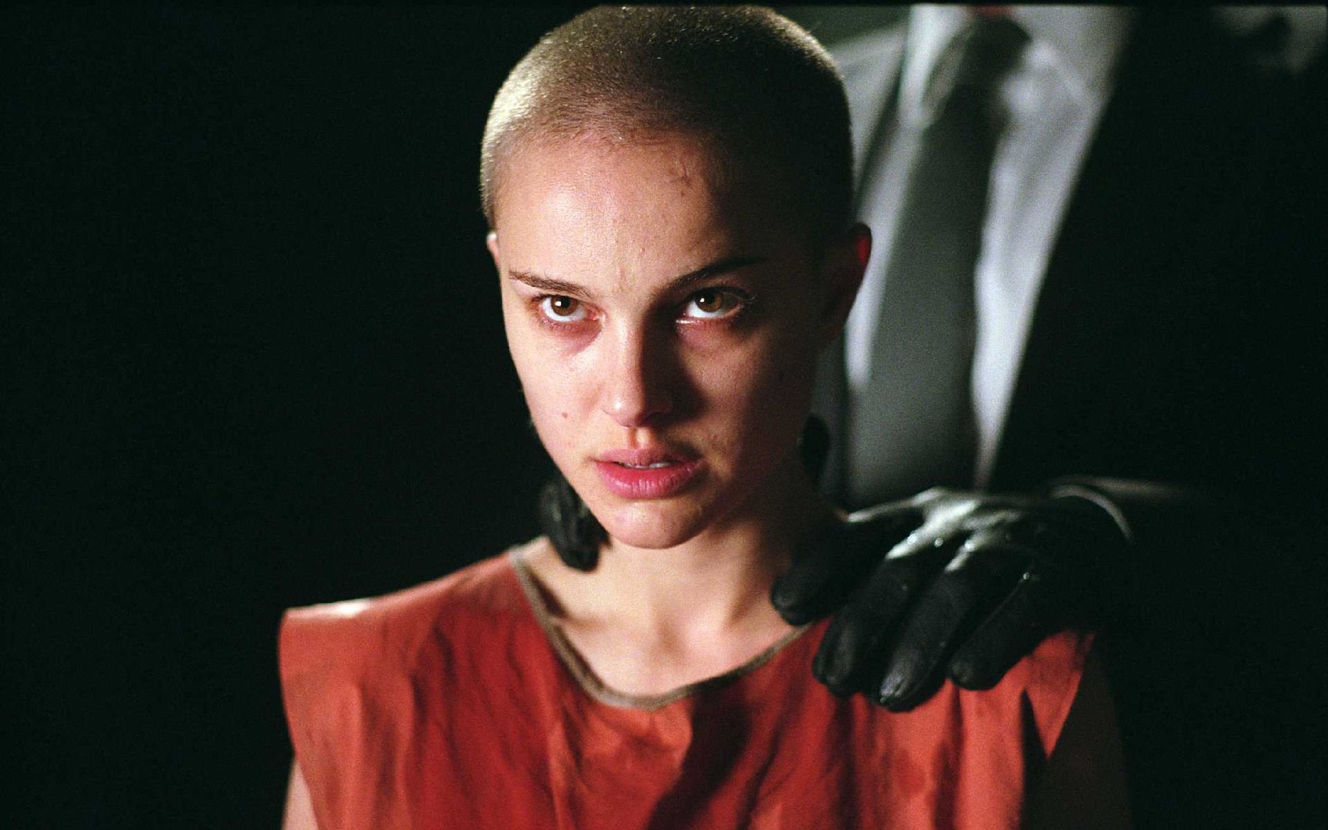 HD PC desktop wallpaper featuring a close-up of Natalie Portman as Evey Hammond from the movie V for Vendetta, with a gloved hand on her shoulder in a dark setting.