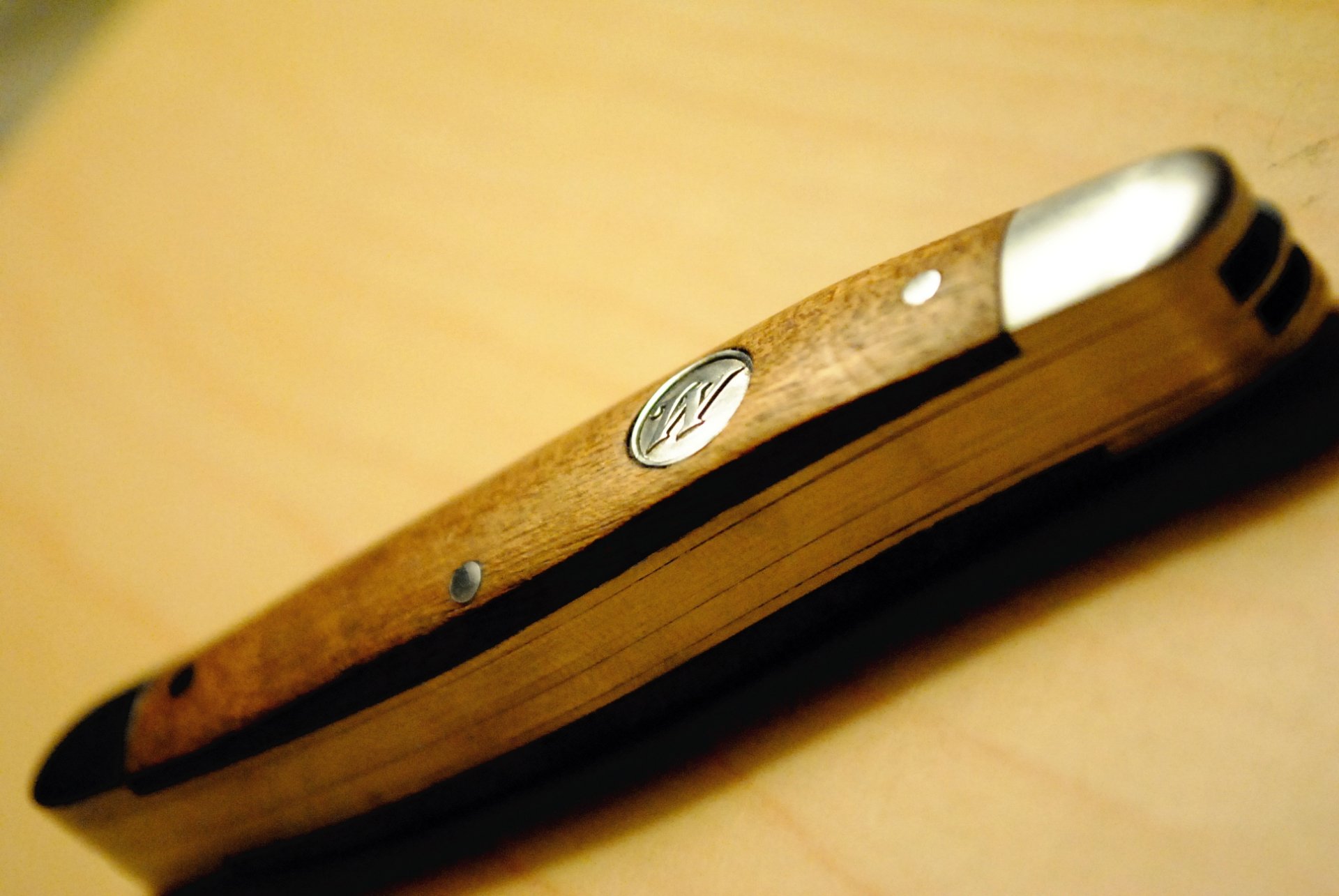 Close-up of a knife with a wooden handle resting on a smooth surface, showcasing its craftsmanship. This HD image serves as a striking PC desktop wallpaper.