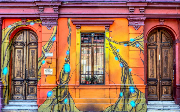 Vibrant man-made facade featuring a colorful orange wall with artistic blue vines, a central window, and two aged wooden doors in 4K Ultra HD detail.