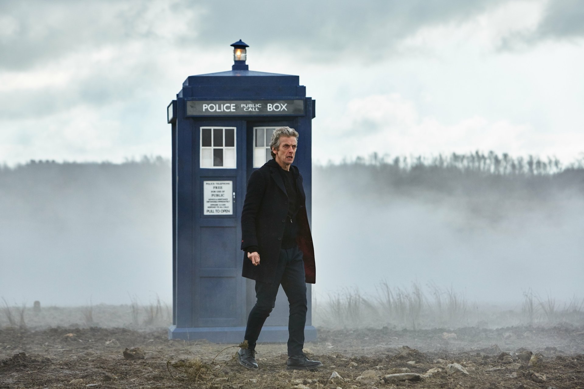 Figure in a dark coat beside a blue police box (TARDIS) in a foggy, desolate field — Doctor Who (2005) TV show 5K Ultra HD desktop wallpaper.