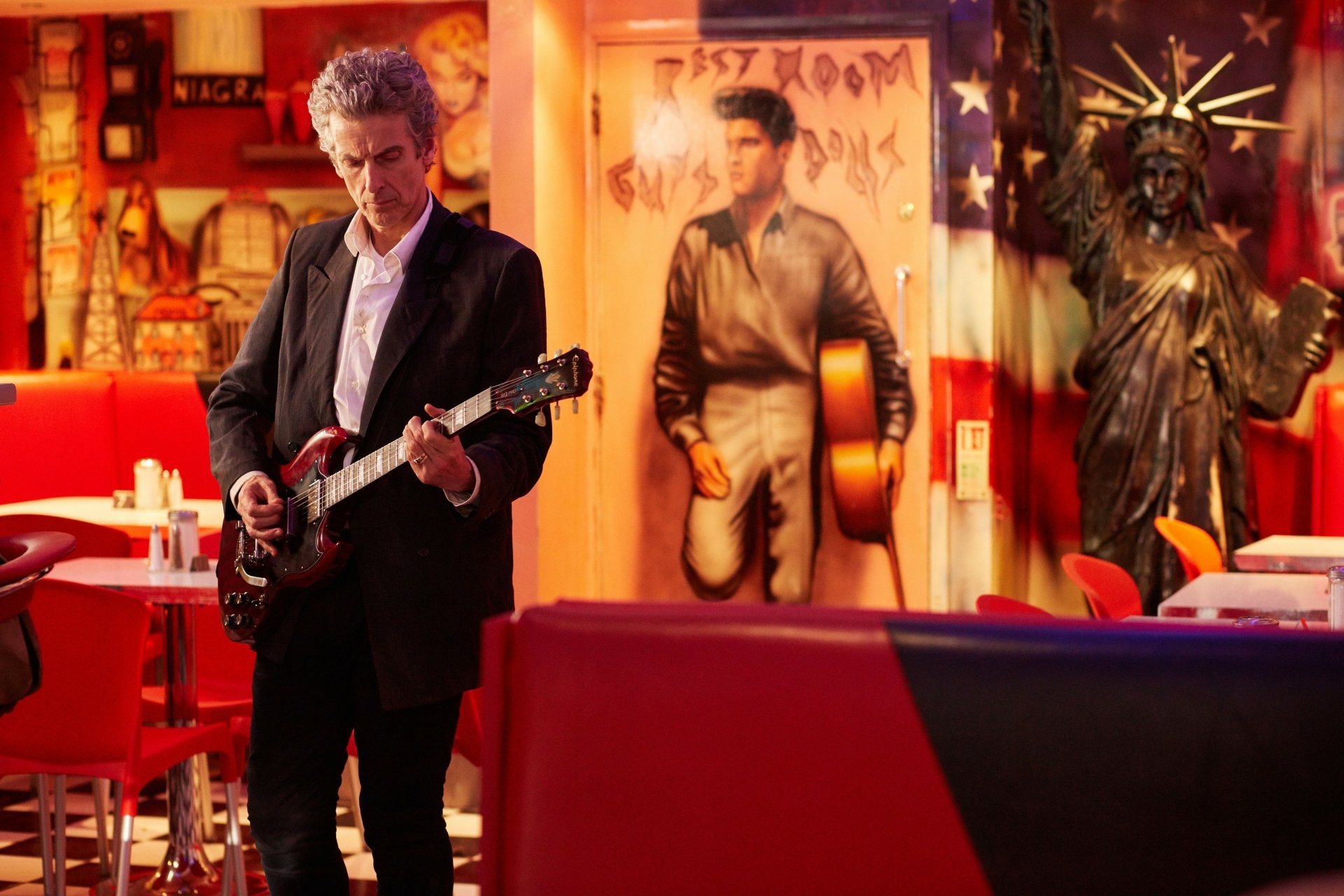 Peter Capaldi as the 12th Doctor playing guitar in a vibrant, retro-styled diner, featured as a 4K Ultra HD desktop wallpaper from Doctor Who (2005).