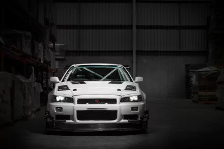 Front view of a white Nissan Skyline GT-R parked in a dimly lit garage, featured as an HD PC desktop wallpaper and background.