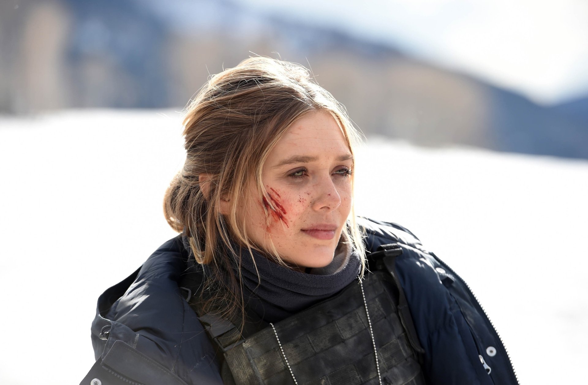 HD desktop wallpaper featuring Elizabeth Olsen in a snowy scene from the movie Wind River, with a focused expression and a slight wound on her cheek.