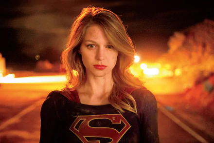 Melissa Benoist as Supergirl stands confidently against a fiery background, showcasing her iconic superhero persona in this HD wallpaper from the TV show Supergirl.