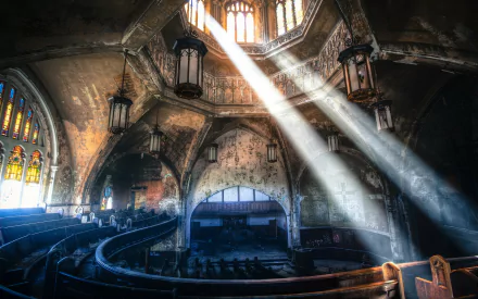 HD wallpaper of an abandoned theater with church architecture, featuring sunbeams streaming through stained glass windows onto the ruin's interior.