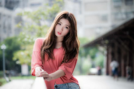 A high-definition desktop wallpaper featuring a brunette Asian model wearing lipstick in a casual setting with a blurred background.