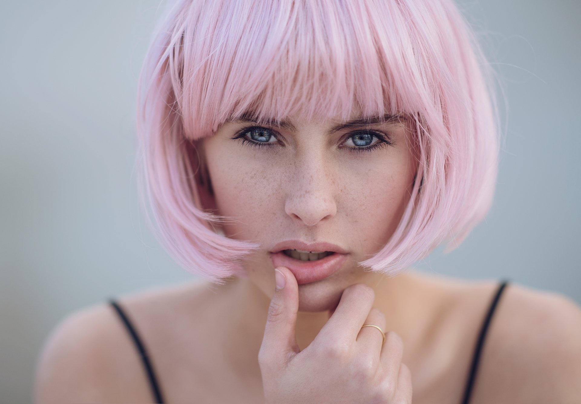 A close-up of a model with short pink hair and striking blue eyes, showcasing her face with a thoughtful expression. This vibrant image serves as a stunning 4K Ultra HD wallpaper.