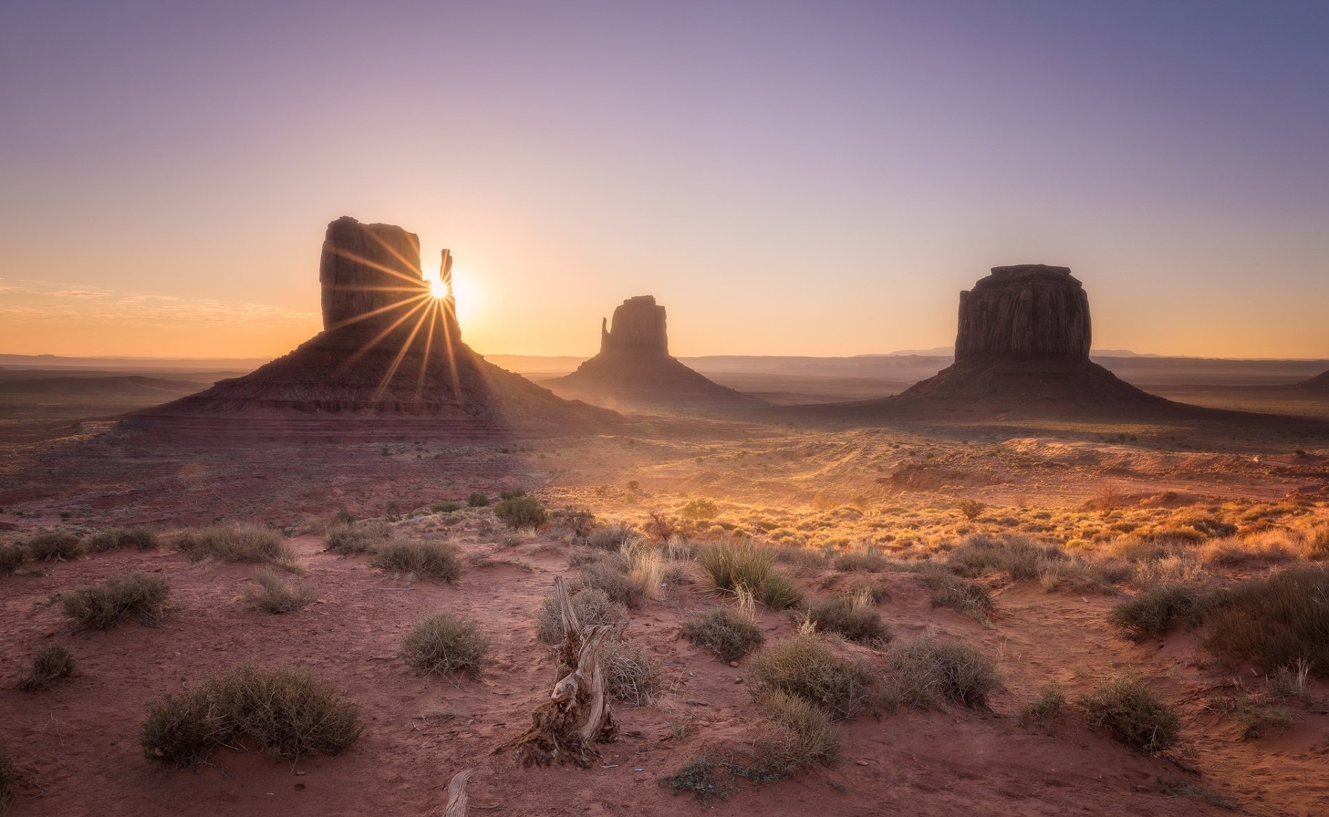Stunning sunrise over Monument Valley in Utah, highlighting the desert landscape with iconic rock formations bathed in warm light. A breathtaking natural scene.
