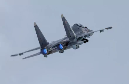 HD desktop wallpaper featuring a military Sukhoi Su-30 jet fighter warplane in flight with afterburners engaged against a clear sky background.